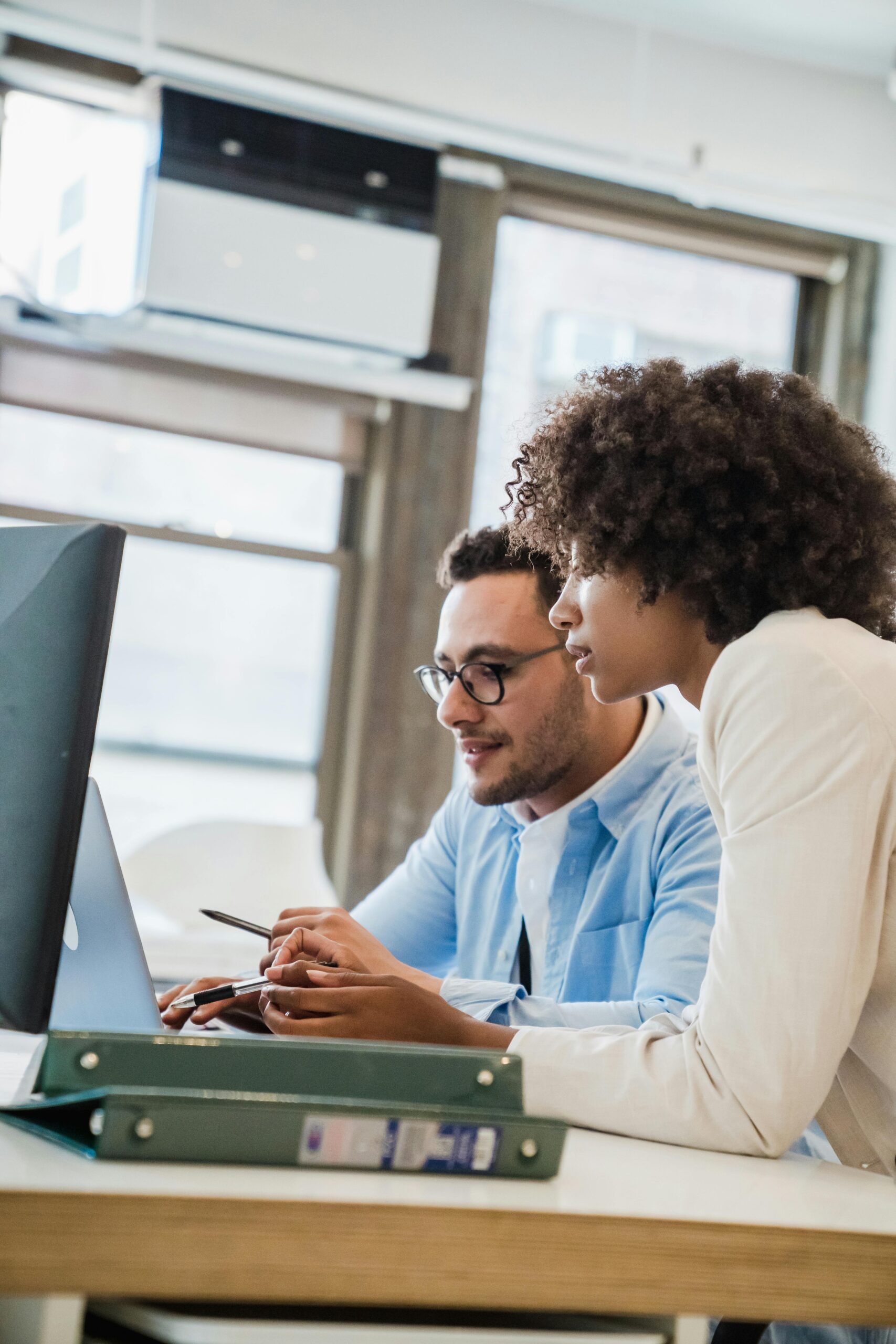 Two professionals collaborating in a modern office setting, focusing on business tasks.